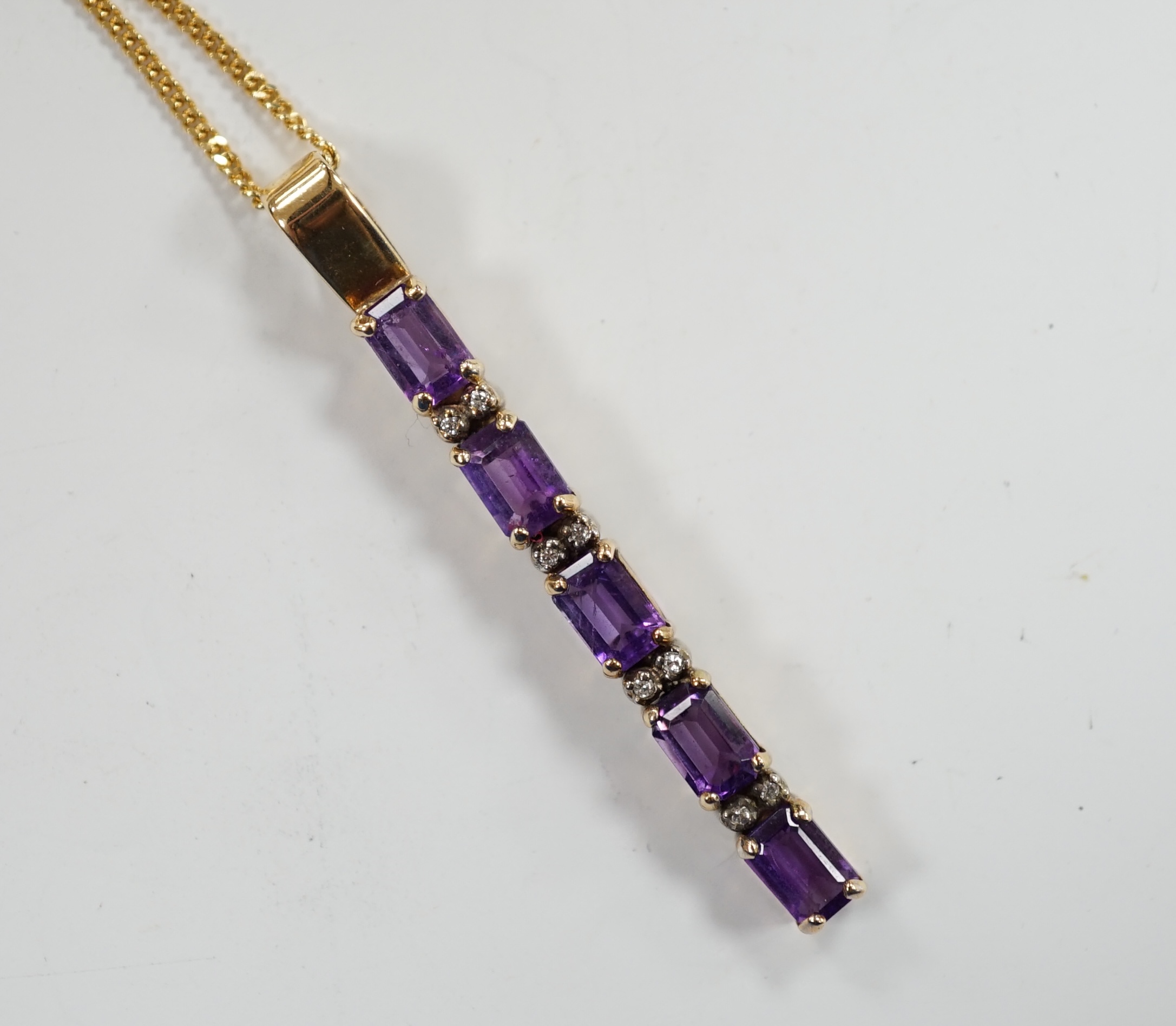 A modern yellow metal, amethyst and diamond chip set line pendant, 47mm, on an 18ct gold fine link chain, 38cm, gross weight 6.4 grams.